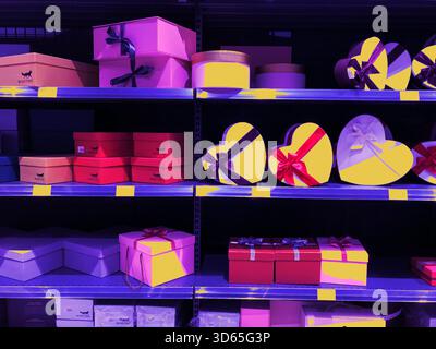 Scatole regalo su scaffali, varie forme e colori, pronte per i regali. Gli scaffali sono pieni di confezioni regalo colorate, perfette per ogni occasione, da birt Foto Stock