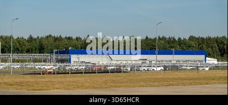 Vista aerea di un ampio parcheggio pieno di auto di nuova produzione in una moderna fabbrica di automobili, pronta per la distribuzione. Foto Stock