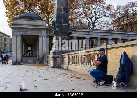 Fotografia documentaria di un musicista di strada (suonatore di tromba) che suona la tromba sul Friedrichsbrücke all'Isola dei Musei, Berlino, Germania. Foto Stock