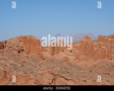 Un canyon rosso parallelo e montagne innevate nebbiose Foto Stock
