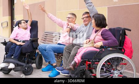 Gruppo eterogeneo di amici con disabilità fisica che alzano le mani insieme Foto Stock