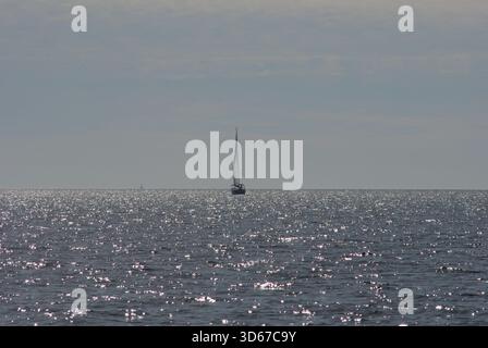 Senza fine e armonia sul grande mare Adriatico con una barca a vela in lontananza sulle onde scintillanti Foto Stock