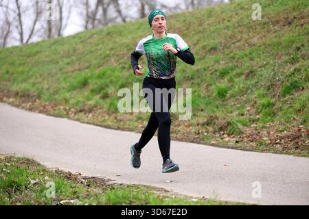 Atleta femminile che si allena all'aperto su un sentiero lastricato del parco Foto Stock