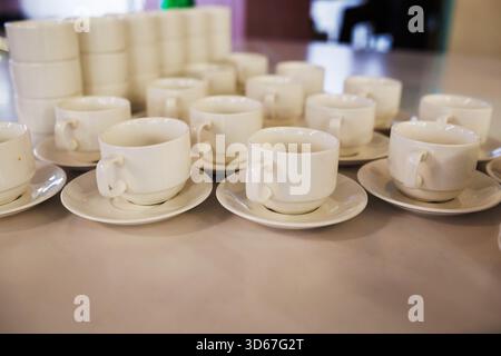 tazze, piattini, cucchiai per la cerimonia del tè su un tavolo da banchetto Foto Stock