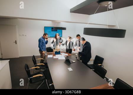 Team che discute idee intorno a un tavolo da conferenza in un ufficio professionale Foto Stock