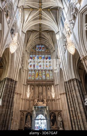 L'intricata architettura gotica caratterizza l'Abbazia di Westminster, con splendide vetrate colorate ed eleganti lampadari che illuminano i vasti interni. I visitatori ammirano la bellezza storica. Foto Stock