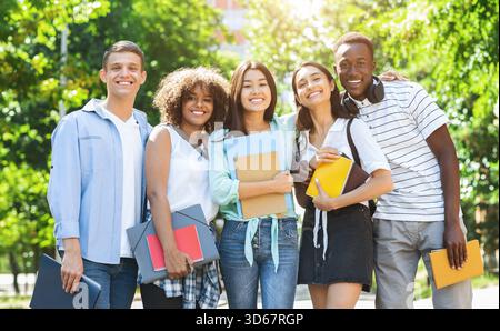 Concetto di amicizia con il college. Felice gruppo multietnico di studenti che si pongono all'aperto Foto Stock