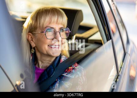 Donna anziana che guarda fuori dal finestrino dell'auto Foto Stock