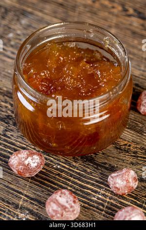 marmellata d'arancia composta da arance e agrumi ed essiccata in sciroppo di zucchero, frutta kumquat intera in polvere bianca, un vaso di vetro con marmellata d'arancia dolce è acceso Foto Stock