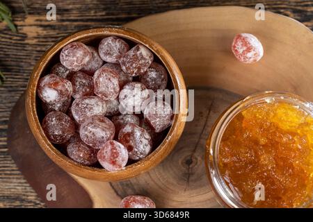 marmellata d'arancia composta da arance e agrumi ed essiccata in sciroppo di zucchero, frutta kumquat intera in polvere bianca, un vaso di vetro con marmellata d'arancia dolce è sul ta Foto Stock