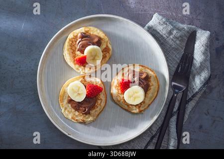 Frittelle con crema al nougat di noci, banana e fragole Foto Stock