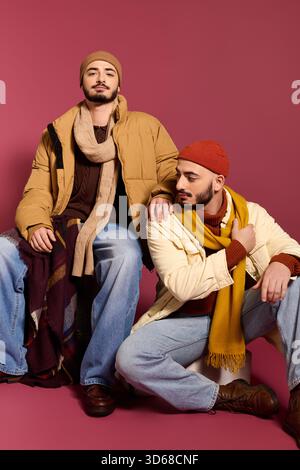 I fratelli mettono in mostra il loro legame e il loro stile unico in abiti alla moda su uno sfondo vivace. Foto Stock