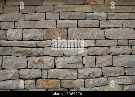 Primo piano ad alta risoluzione di un muro di pietra impilato, texture ruvide e naturali, forme irregolari e toni terrosi. Ideale per sfondi antichi, Foto Stock