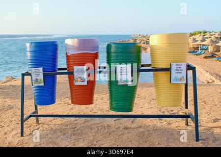 Quattro bidoni colorati per la raccolta differenziata dei rifiuti in spiaggia. Foto Stock