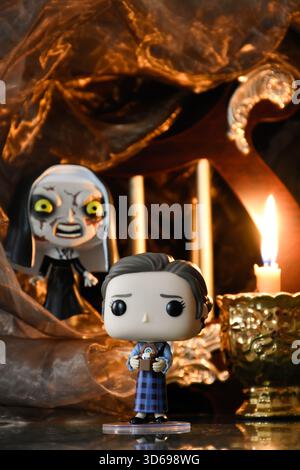 Funko Pop action figure di Lorraine Warren e la suora del film horror Conjuring. Antico tempio buio, la candela accesa brucia nel semi-buio. Foto Stock