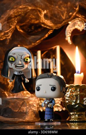 Funko Pop action figure di Lorraine Warren e la suora del film horror Conjuring. Antico tempio buio, la candela accesa brucia nel semi-buio. Foto Stock