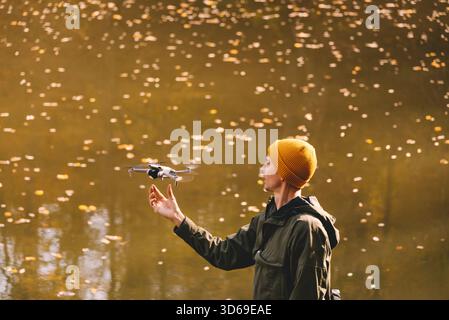 Man Flying Drone contro Autumn Lake Foto Stock