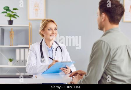 Medico donna che parla con un paziente di sesso maschile che prende appunti negli appunti ascoltando un paziente di sesso maschile Foto Stock