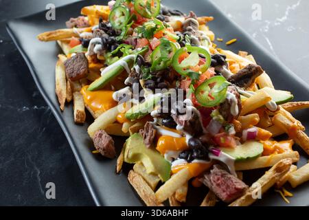 Vista ravvicinata di un piatto di patatine fritte di carne asada. Foto Stock