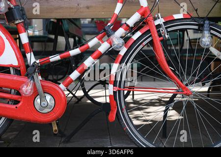 Vista ravvicinata di una bicicletta decorativa rossa e bianca con luci in un accogliente ambiente da caffetteria Foto Stock