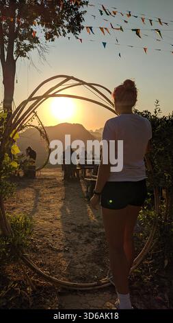 Samet Nangshi - le pittoresche scogliere calcaree della Baia di Phang Nga offrono vedute mozzafiato. Una ragazza in pantaloncini corti, con la schiena alla telecamera, guarda l'alba. Foto Stock