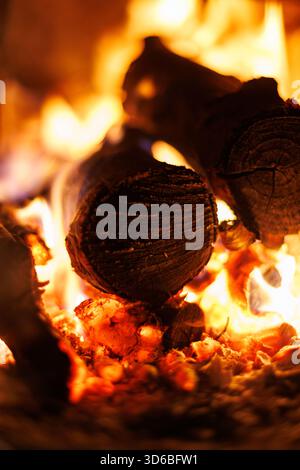 Tronchi bruciati nel caminetto. Primo piano di legna da ardere e fiamme arancioni accese all'interno di un caminetto - calore accogliente e comfort invernale. Foto Stock