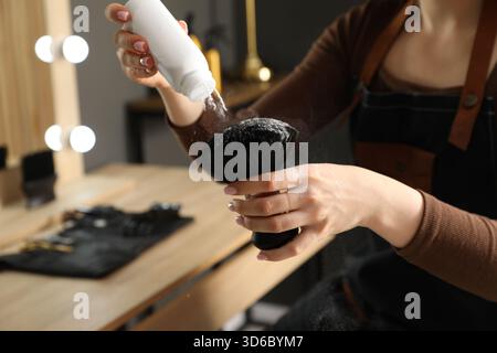 Parrucchiere che mette polvere di talco sulla spazzola al salone, primo piano Foto Stock