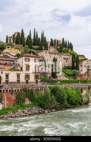 Vista panoramica di una città italiana lungo un fiume, edifici storici che si riflettono nelle acque calme sotto il cielo limpido, che mostrano un'architettura affascinante. Foto Stock