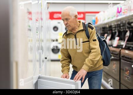 senor uomo pensionato acquistare frigorifero in showroom di elettrodomestici negozio Foto Stock
