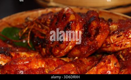 Gamberi grigliati speziati indonesiani ricoperti di salsa al peperoncino rosso, serviti su foglie di banana nel cestino di bambù. Autentica cucina asiatica a base di pesce, tradizionale Foto Stock