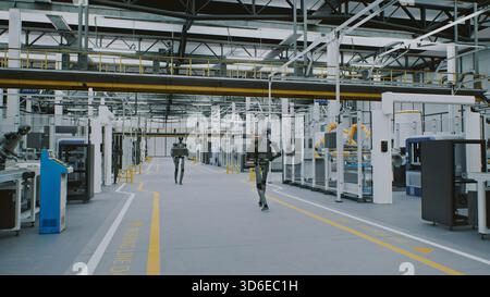 Robot umanoidi che lavorano automazione e intelligenza artificiale nella moderna fabbrica futuristica. Robot Android che spostano le apparecchiature in ambienti industriali puliti e automatizzati. Concetto di futuro del lavoro e automazione basata sull'intelligenza artificiale. Foto Stock
