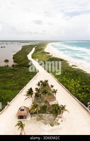 Vista aerea che mostra un sentiero tortuoso sulla spiaggia tra vegetazione lussureggiante e limpide spiagge sull'isola di Cozumel. Questo tranquillo paesaggio mette in risalto l'untouc Foto Stock