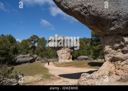 In lontananza, una donna irriconoscibile cammina da sola tra le formazioni rocciose uniche di la Ciudad Encantada, Cuenca, Castilla-la Mancha, Spagna, vetrina Foto Stock