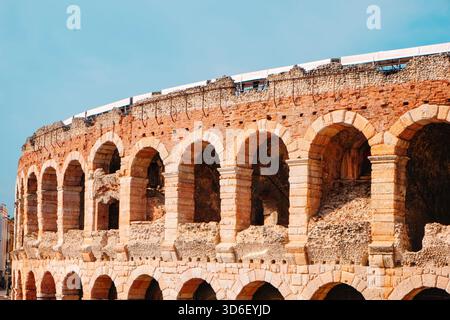 Archi romani illuminati dal sole dell'Arena di Verona, in Italia, mentre l'anfiteatro mostra le sue texture logore e le delicate tonalità di pietra arancione Foto Stock