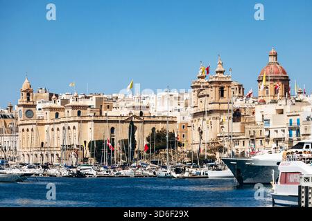 Birgu, Malta? 11 aprile 2025: Vista panoramica dal porticciolo di Birgu verso lo storico lungomare di Senglea con chiese, cupole, famose torri e yacht lungo la costa mediterranea Foto Stock