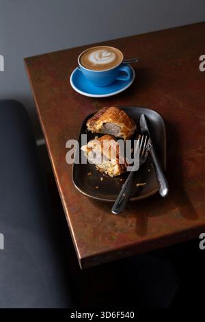 Latte art, tazza di caffè seduta su un ricco tavolo da caffè in rame con riflessi della finestra, caffè sul tavolo Foto Stock