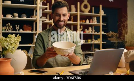 Felice gioioso uomo caucasico uomo d'affari uomo uomo d'affari uomo imprenditore imprenditore artigiano ceramista che scrive laptop online che controlla la porcellana del prodotto Foto Stock
