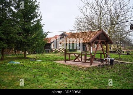 gazebo in legno con la natura circostante, gazebo panoramico sul cortile con panchine e cielo invernale sullo sfondo Foto Stock