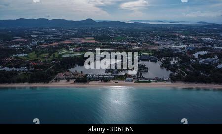 Ampia vista aerea di un'ampia spiaggia tropicale, dell'oceano cristallino e di un enorme complesso di resort di lusso costruito intorno a laghi artificiali Foto Stock