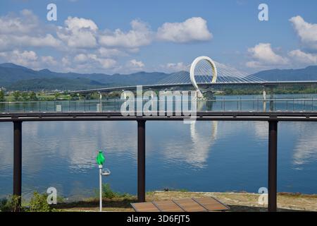 Dalla foresta di Munhwa Gwangjang, il Gran Ponte di Chuncheon attraversa il lago Uiam sullo sfondo di acque calme, montagne circostanti e cieli limpidi lungo il fiume Foto Stock