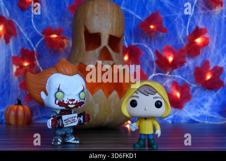 Funko Pop action figure di clown Pennywise e Georgie del film horror IT. Arredamento di Halloween, Jack o lanterna, ragnatela, foglie, luci. Foto Stock