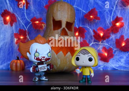 Funko Pop action figure di clown Pennywise e Georgie del film horror IT. Arredamento di Halloween, Jack o lanterna, ragnatela, foglie, luci. Foto Stock