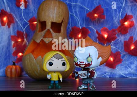 Funko Pop action figure di clown Pennywise e Georgie del film horror IT. Arredamento di Halloween, Jack o lanterna, ragnatela, foglie, luci. Foto Stock