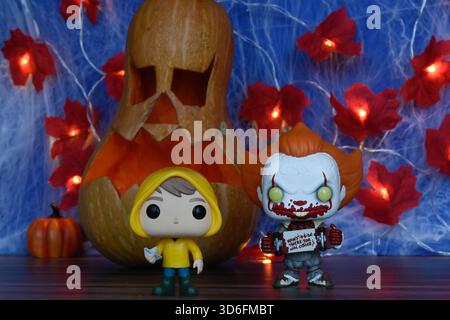 Funko Pop action figure di clown Pennywise e Georgie del film horror IT. Arredamento di Halloween, Jack o lanterna, ragnatela, foglie, luci. Foto Stock