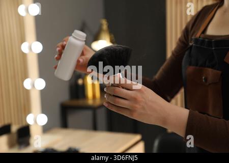 Parrucchiere che mette polvere di talco sulla spazzola al salone, primo piano Foto Stock