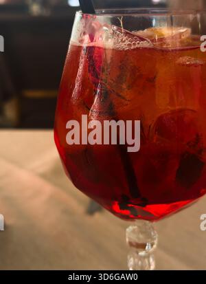 Bicchiere con cocktail Aperol Spritz, con cubetti di ghiaccio e paglia nera su un tavolo in un ristorante. Cocktail Negroni Foto Stock