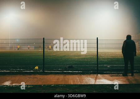 Scena notturna di campi da calcio con giocatori in autunno, atmosfera nebbiosa. Foto Stock
