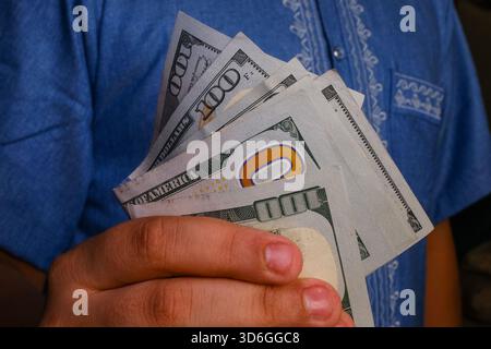 Bassora, Iraq - 5 agosto 2025: Una mano che tiene una pila di banconote americane da cento dollari Foto Stock