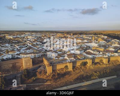 Vista aerea della luce del sole dorata che bagna le antiche mura e i tetti bianchi del Castillo de los Guzmanes e le labirintiche strade della città, Foto Stock