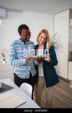 Diverse donne e colleghi che collaborano con un tablet digitale in ufficio Foto Stock